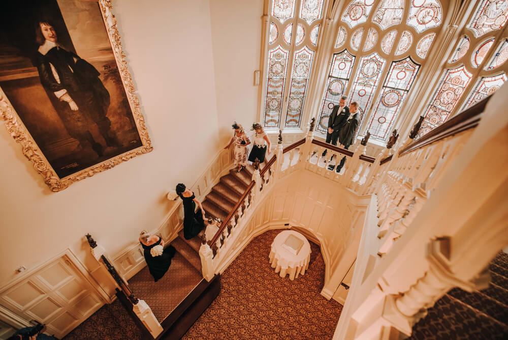 Aaron and Keith walk down stairs at their gay wedding Hampshire at The Elvetham photographer DM Photography 1 5