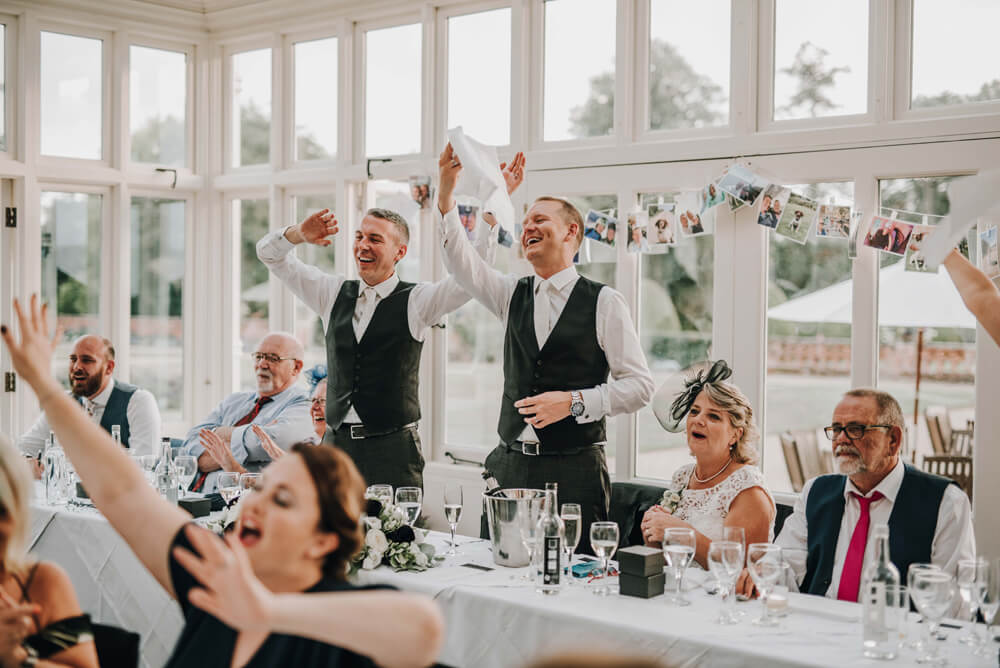 Aaron and Keith wave napkins at their gay wedding Hampshire at The Elvetham photographer DM Photography 1 5
