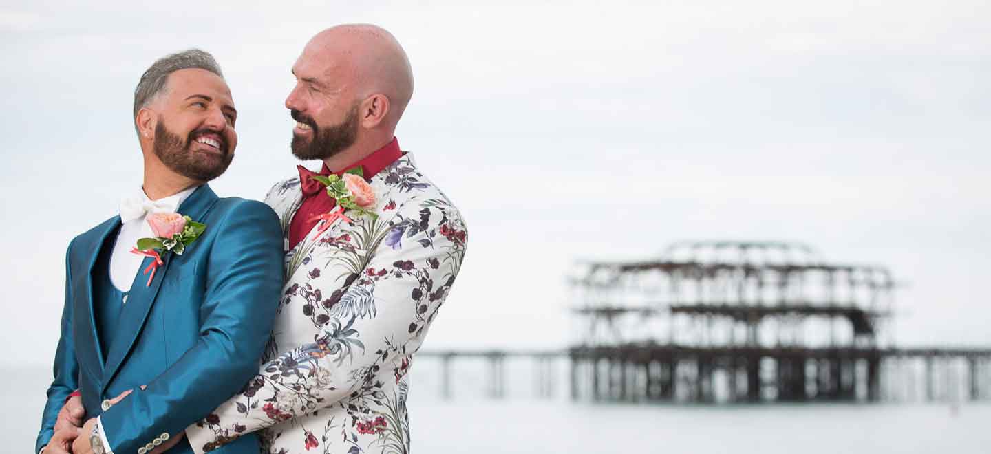Chris and Tony Real Gay Wedding at the Grand hugging near Brighton Pier via The Gay Wedding Guide 1