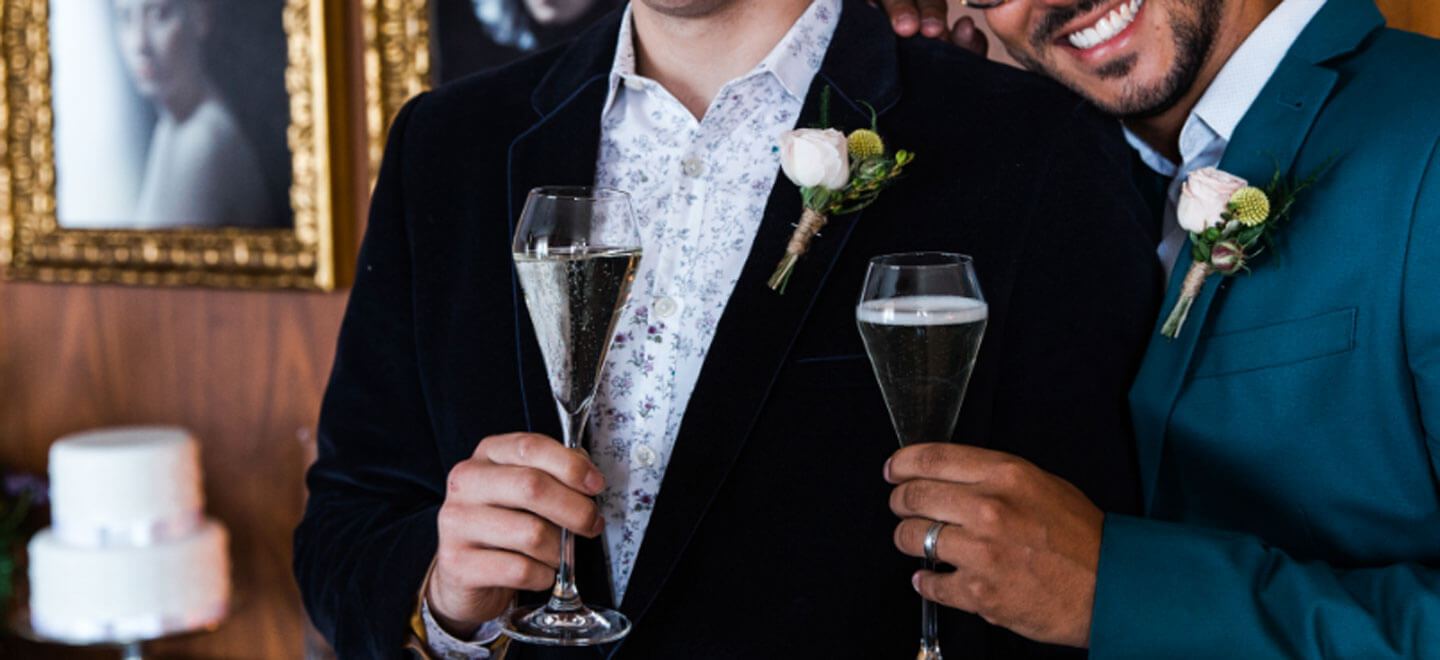 Grooms clink champagne glasses at The London EDITION hotel soho wedding venue gay wedding guide 9