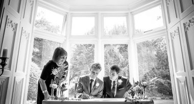 Grooms Sign The Register At Their Gay Wedding In Manchester Image By James Tracey Photography A Gay Wedding Photographer In Manchester Via The Gay Wedding Guide 3 5 380X204