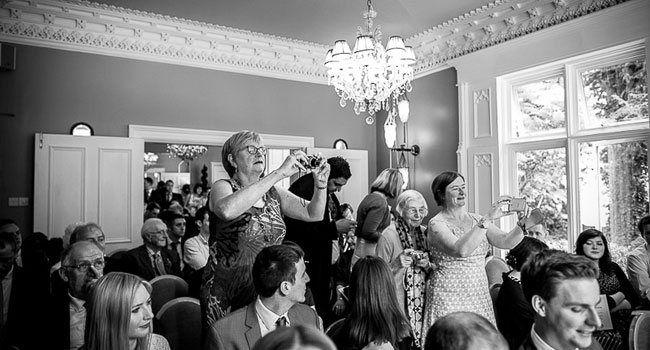Guests take photos during ceremony image shot a manchester gay wedding by James Tracey Photography a gay wedding photographer in Manchester via the Gay Wedding Guide 3 5