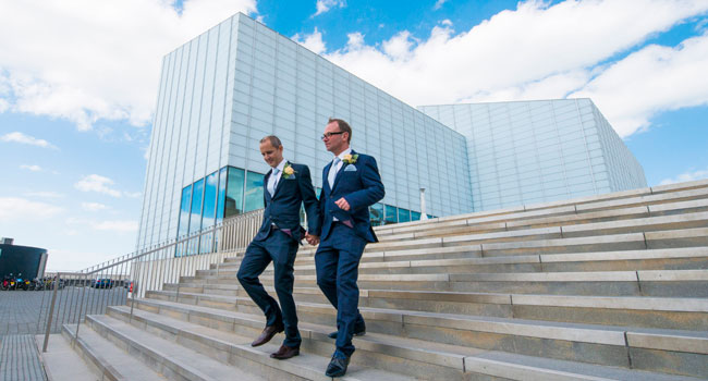 Guy and Andrew walk down the steps of the Turner Contemporary Margate after their same sex wedding photo by Webb Weddings 4 5