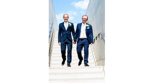 Guy and Andrew walk down the steps outside the Turner Contemporary Margate after their same sex wedding photo by Webb Weddings 3 5