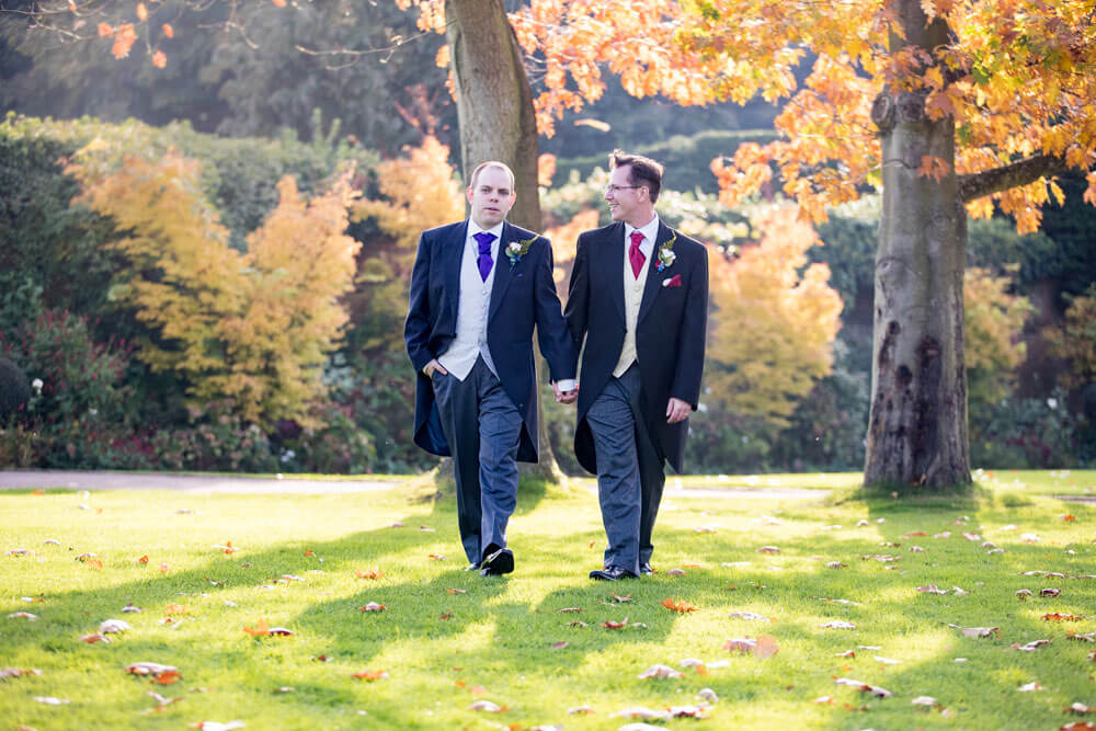 Guy and Mark walk in autumn field at their gay wedding Gaynes Park image copyright Steve Hobart Photography via the gay wedding guide 1 5