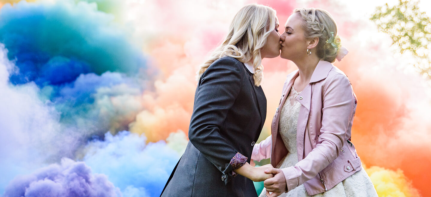 Hemmingway Tailors Suits for Brides at Lesbian wedding with rainbow smoke backdrop via Gay Wedding Guide 6
