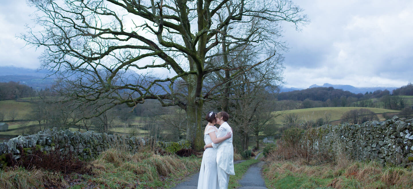Jak and Jules kiss overlooking the hills at their lesbian wedding image copyright Ragdoll Photography via The Gay Wedding Guide 3 5