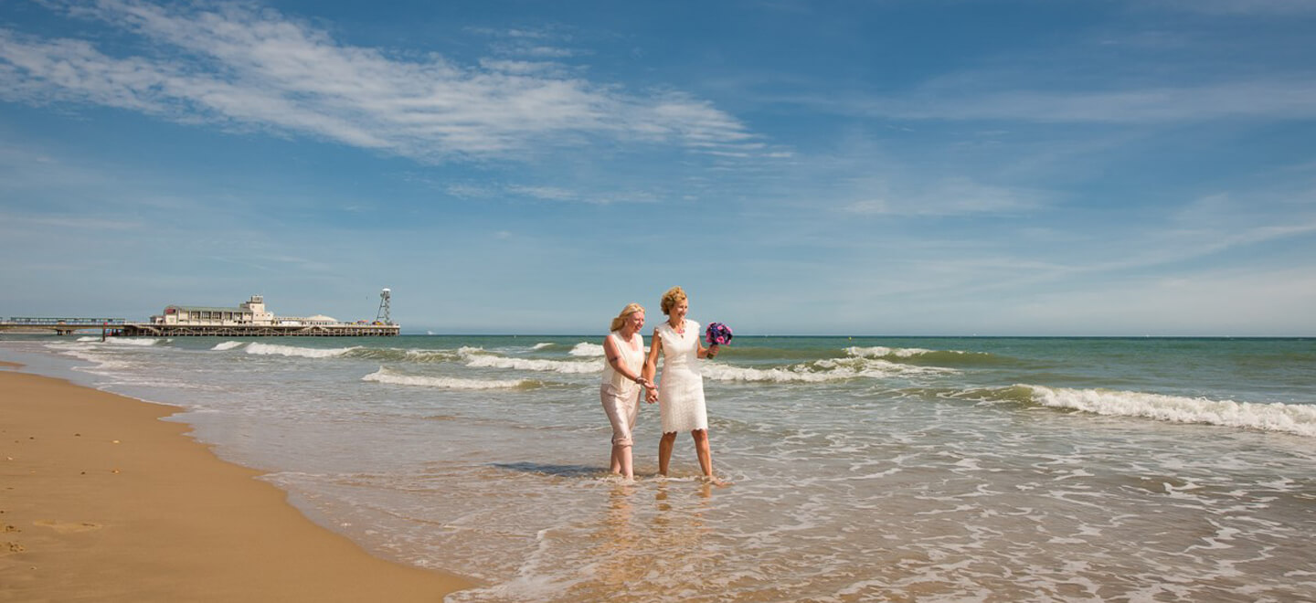 Lesbian beach Wedding Bournemouth Couple walk along the shore via Gay Wedding Guide 9