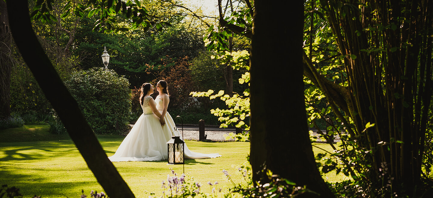 Lesbian brides embrace in garden at Old Rectory wedding venue Worcester gay wedding guide 9