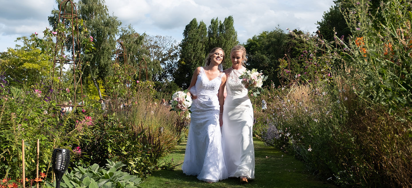 Lesbian brides walking in garden at Wakehurst a gay wedding venue West Sussex image via The Gay Wedding Guide 9