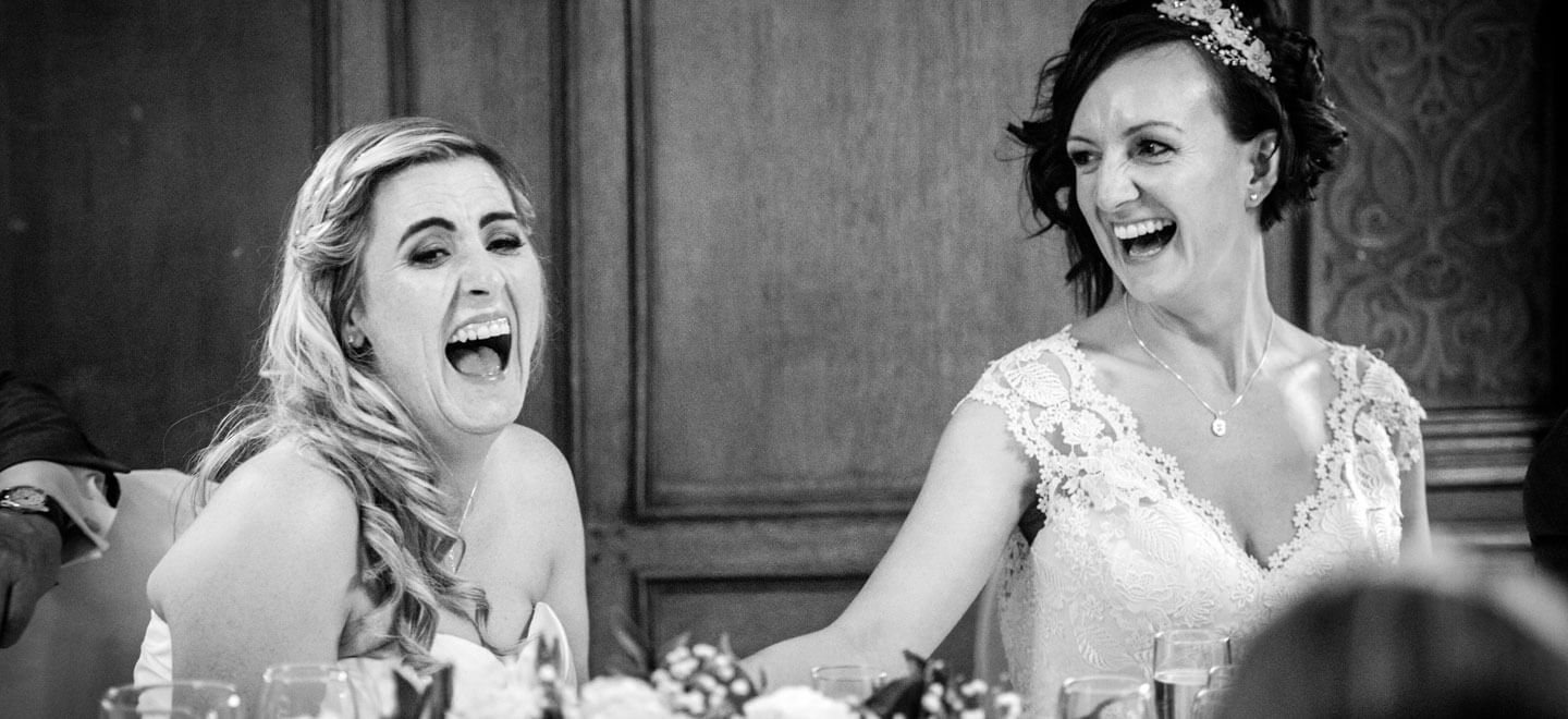 Lynsey and Joanne laughing during wedding breakfast by James Tracey gay wedding photography via the gay wedding guide 6
