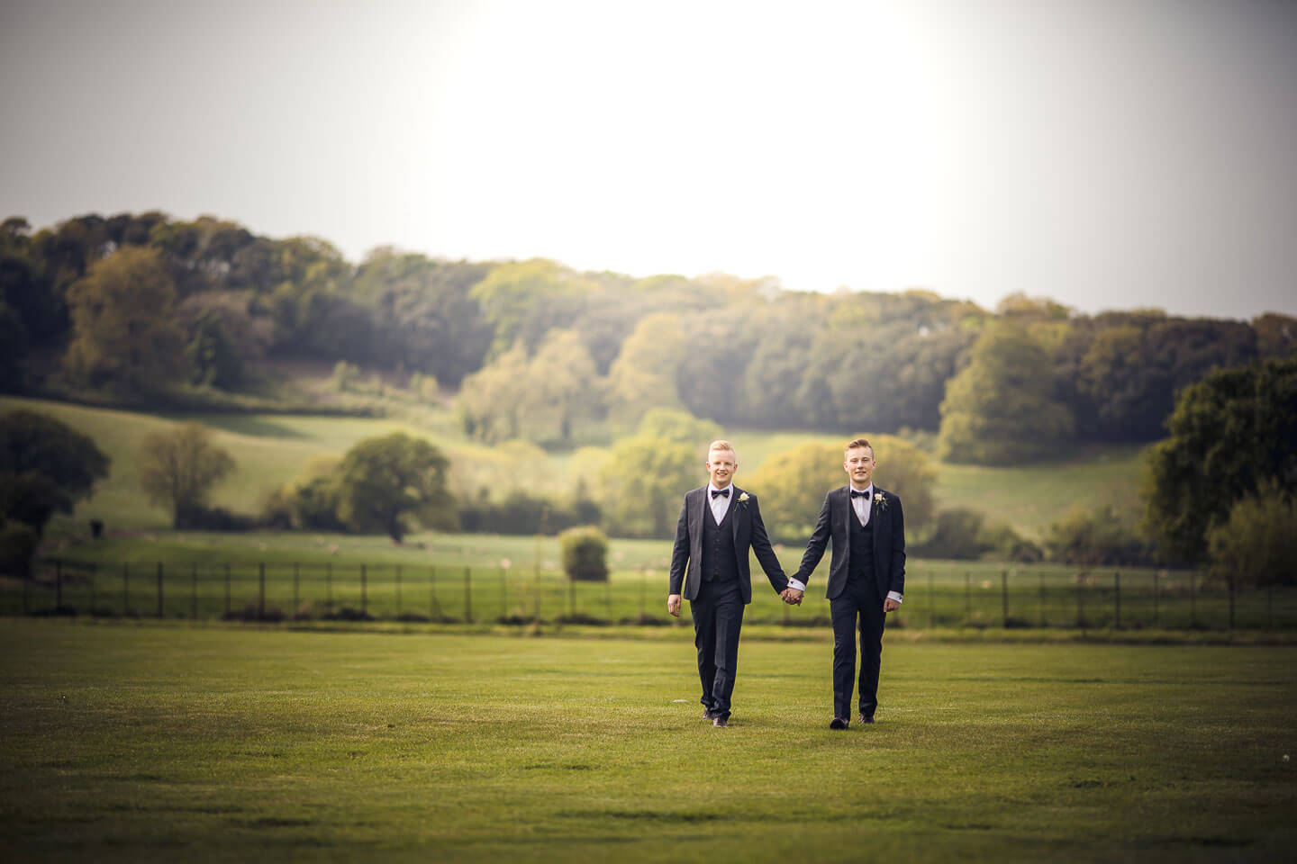 Sam and Kyle gay wedding photos walk across a field image copyright Shooting Pixels featured on The Gay Wedding Guide 3 5