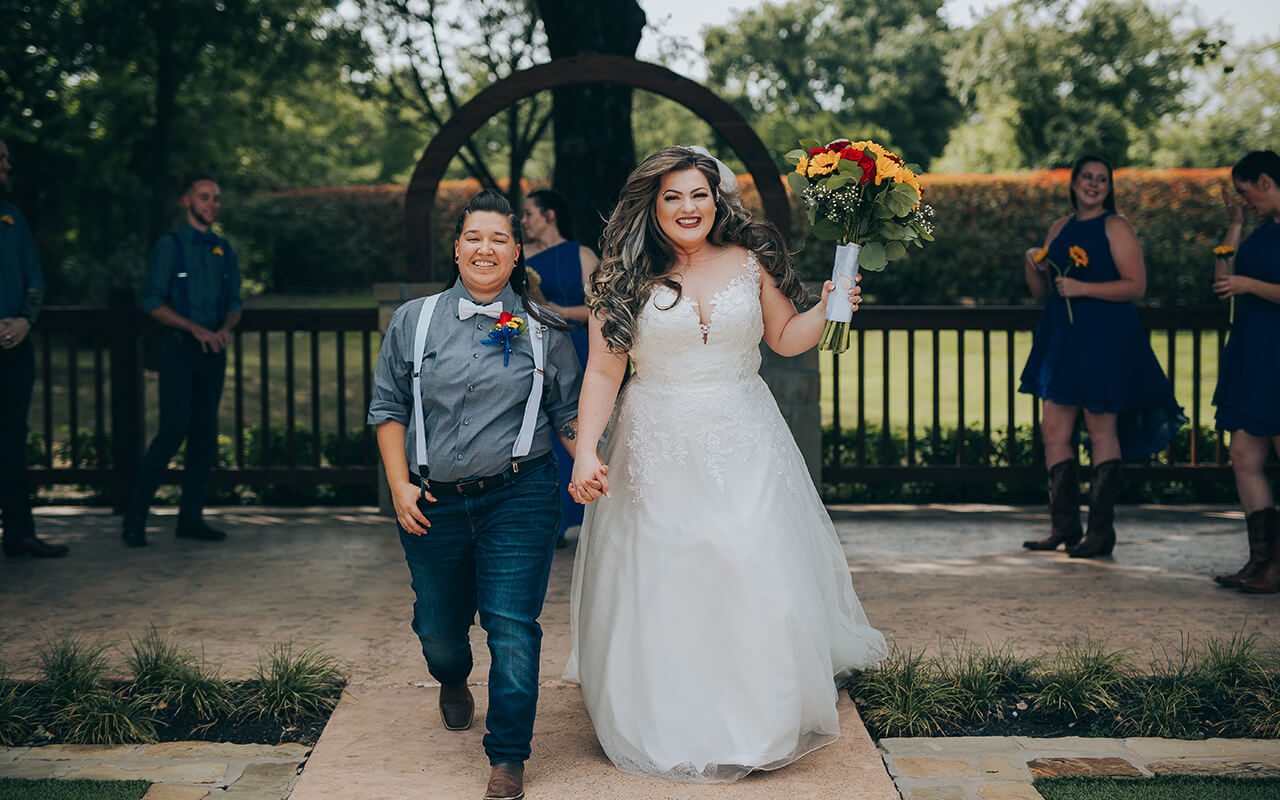 lesbian bride and goom walking to the isle photo by tara arseven tap 5 6