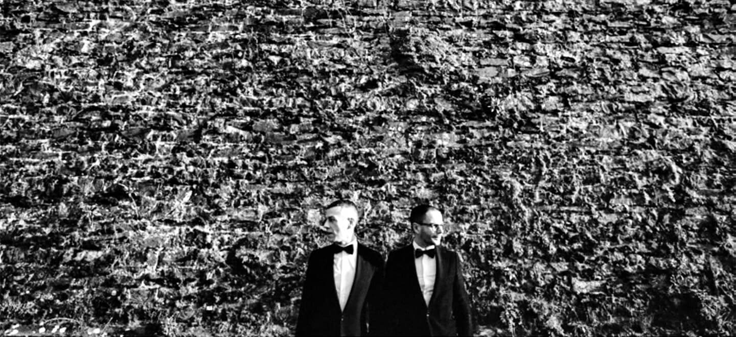 orchestra weddings gay couple facing outwards by a big wall 6