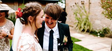 Two Lesbian Brides Hugging And Laughing At Upcote Barns In Cotswolds Via Gay Wedding Guide Dan Walker 9 380X174