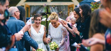 Two Lesbian Brides Walking End Of Ceremoney At Upcote Barns In Cotswolds Via Gay Wedding Guide Noel Hibbert 9 380X174