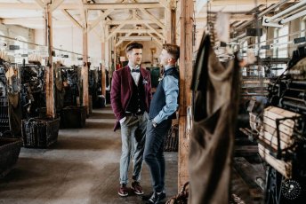 Gay Couple Lean Against Post In Styeld Gay Engagement Shoot At Germany Fabric Factory.1 Image By Juliabartelt 1 5 344X230