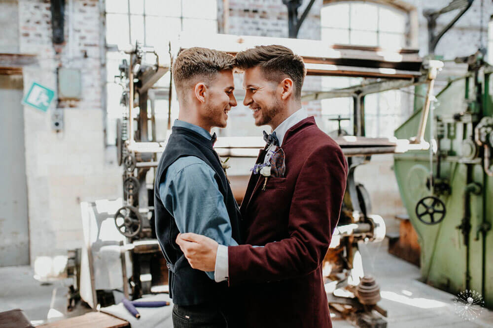 Grooms embrace at styeld gay wedding shoot at Germany fabric factory.1 Image by JuliaBartelt 1 5