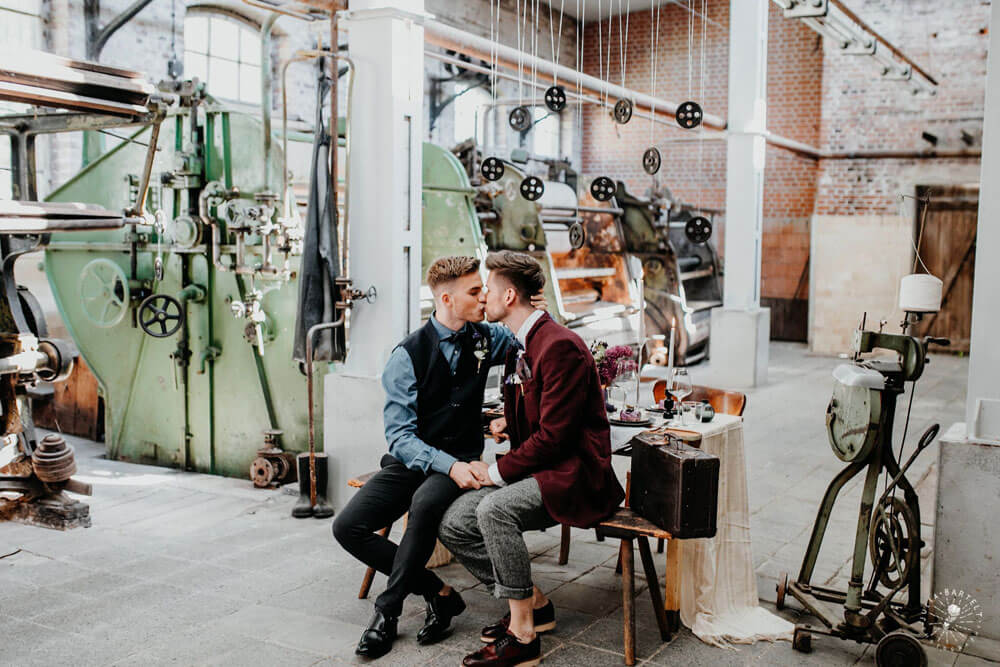 Grooms kiss at styled gay wedding shoot at Germany fabric factory.1 Image by JuliaBartelt 1 5