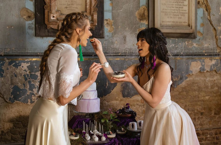 Models as brides feeding each other at Gothic and Purple wedding ideas Styled Shoot via The Gay Wedding Guide 1 5