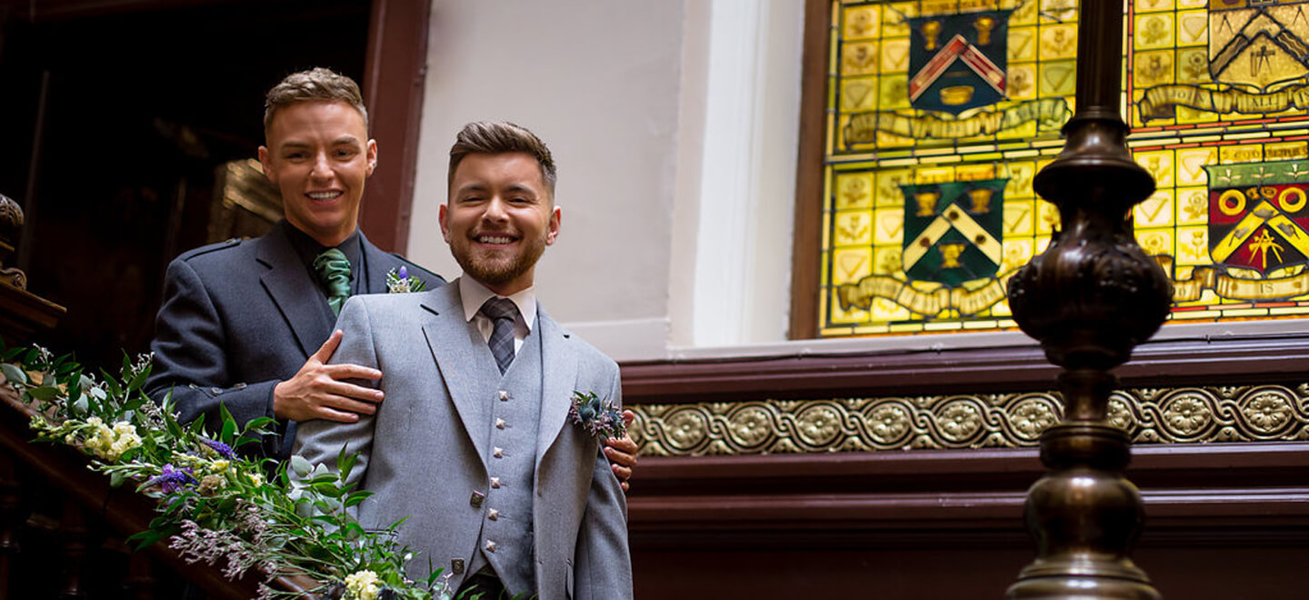 Couple On Stairs By Stained Glass Window At Scottish Theme Wedding Style By Love Cat D At Trades Hall Via Gay Wedding Guide 2 - Experts At Work: Scottish Gay Wedding Theme Gay Wedding Guide